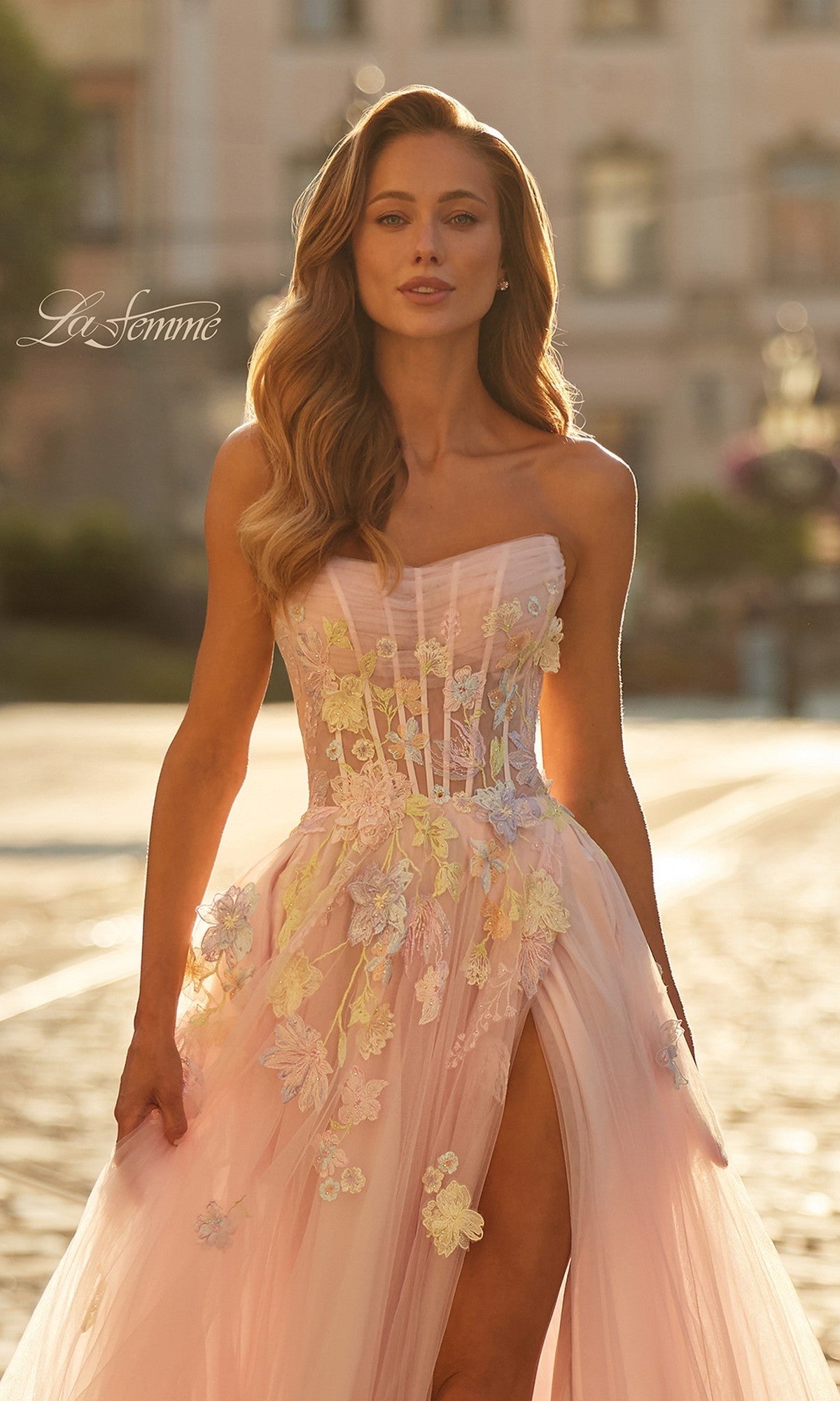 Woman in the La Femme 33432 long prom dress—strapless, pastel pink with floral appliqué and a thigh-high slit—standing outdoors in sunlight;
